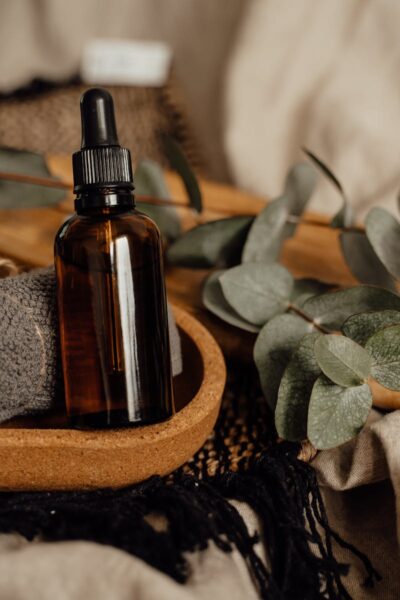 flacon d'huile et plantes Still life of an amber glass bottle with eucalyptus and towel on a wooden tray.